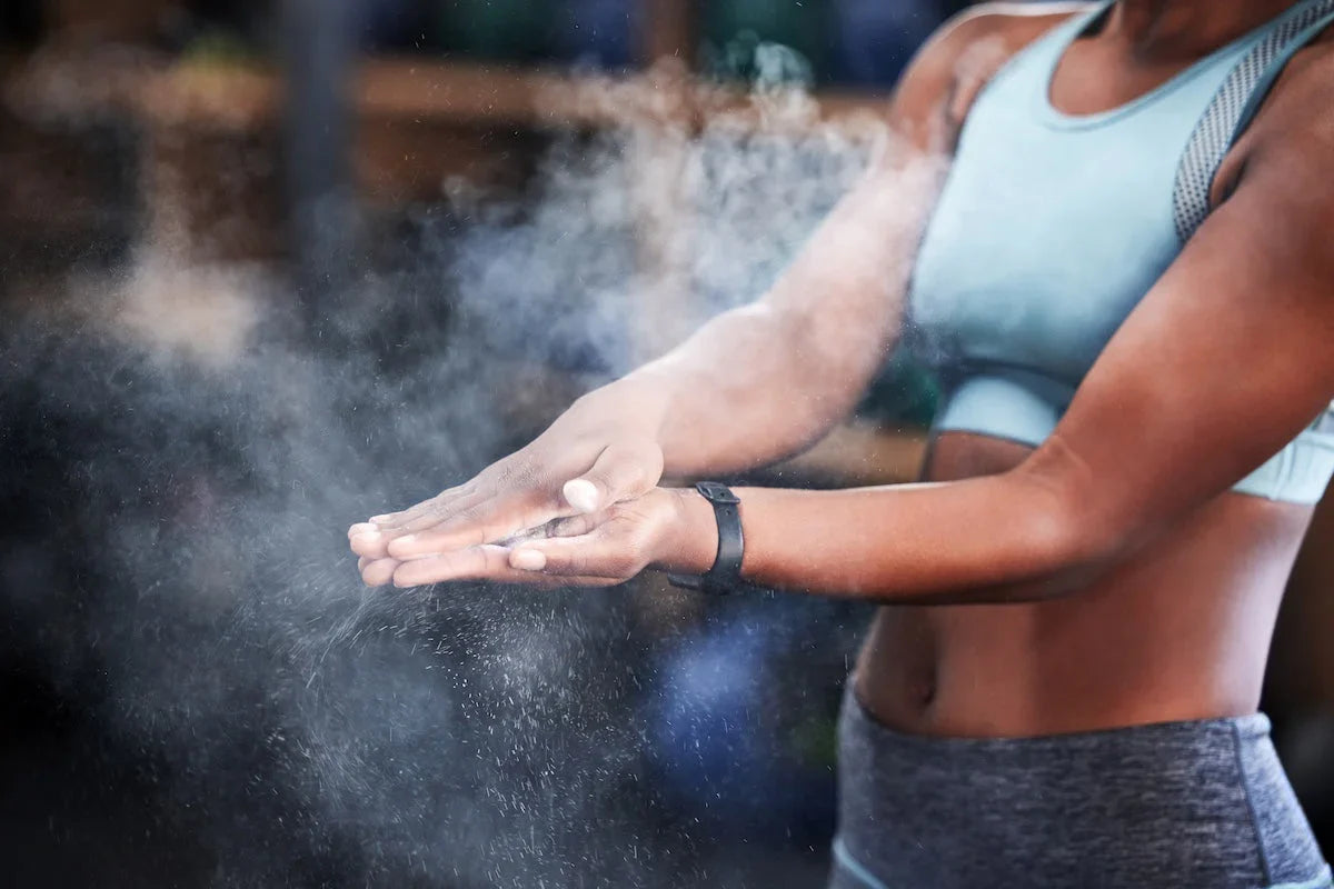 Fit woman in sportswear clapping chalk dust from her hands before a workout at the gym.