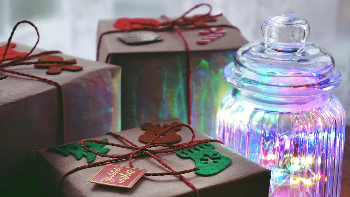 Beautifully wrapped Christmas presents next to a glowing jar of colorful lights, creating a warm and festive holiday atmosphere.
