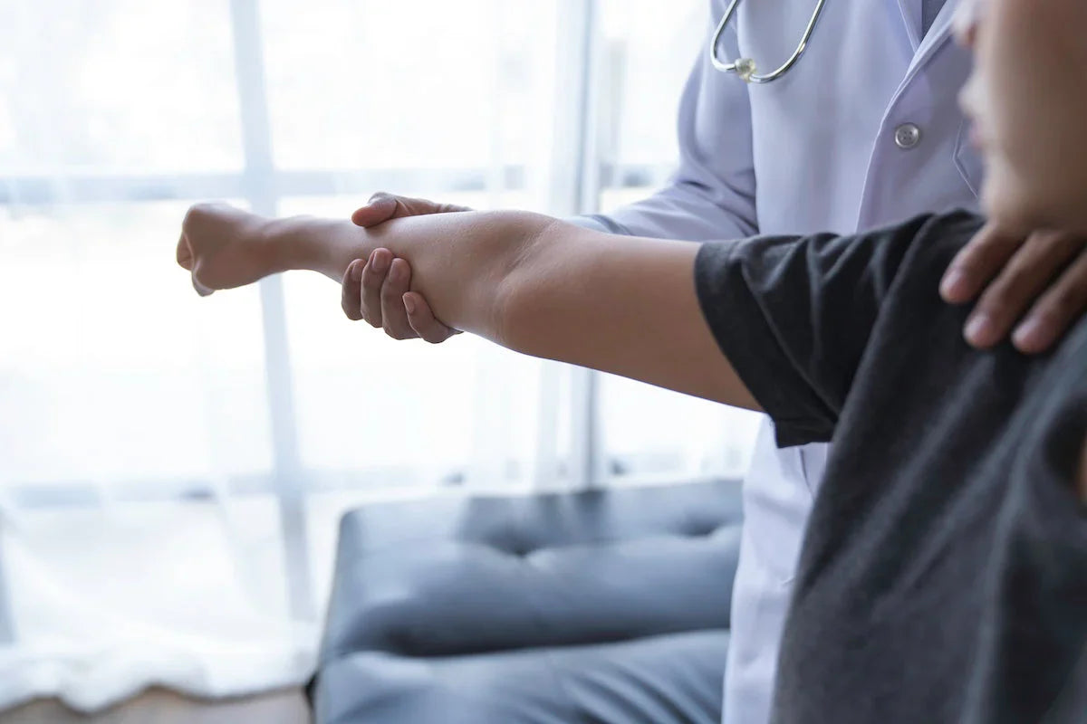 Doctor examining a patient’s arm during a medical consultation, checking for pain or mobility issues.