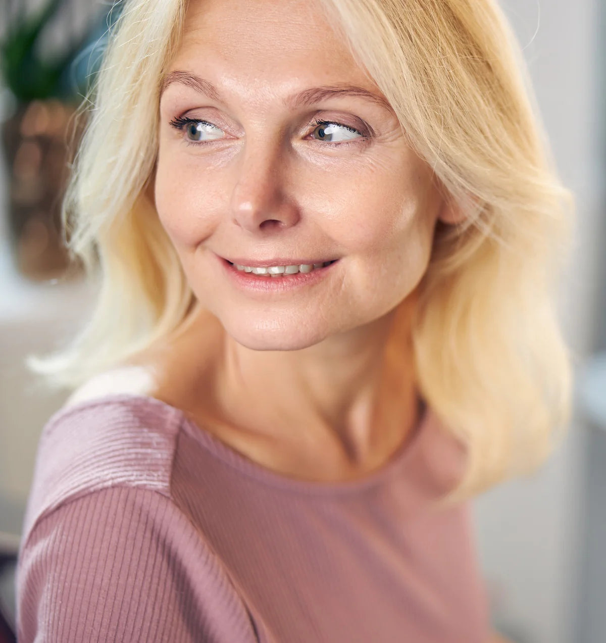 Woman with blonde hair and a pink sweater looking to the side.